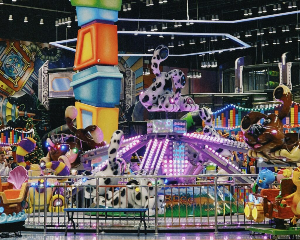 Colorful carousel at an indoor amusement park in Almaty, featuring whimsical animal designs and bright lights.