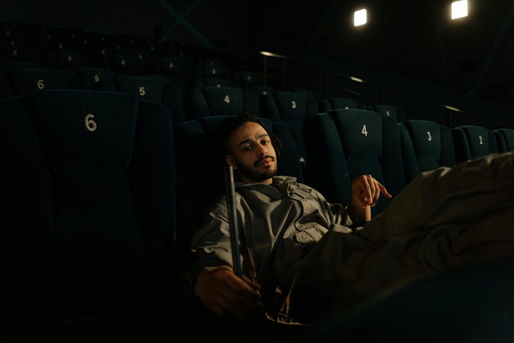 Man in uniform resting on cinema seats during a quiet moment at work.