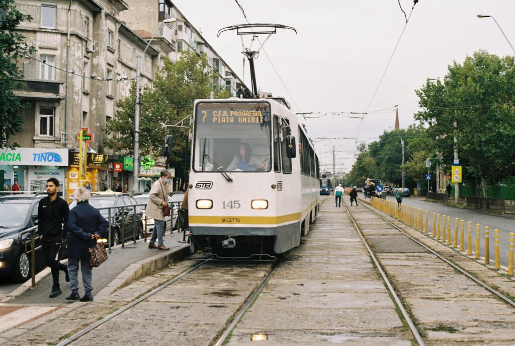 A tram at a city station with commuters in a lively urban setting.