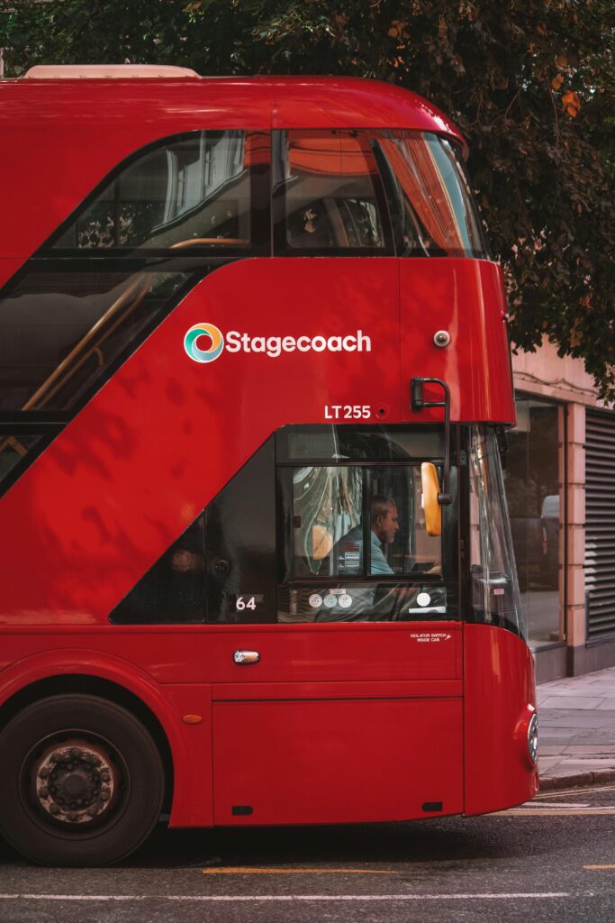 A classic red double decker bus traverses the urban streets of London, showcasing public transportation in the city.