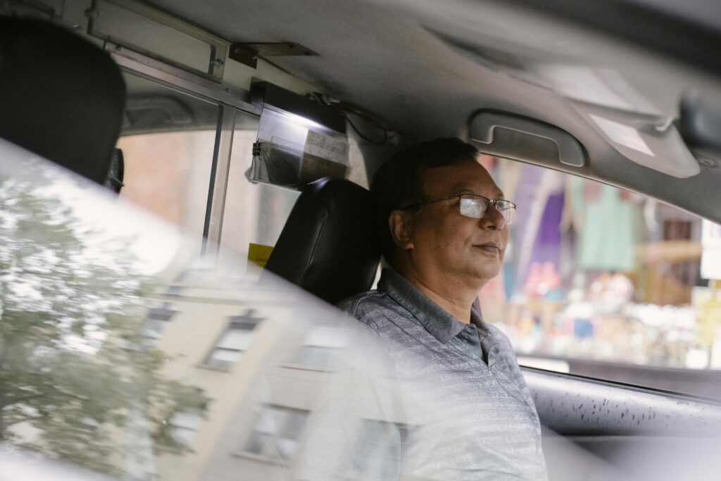 Calm middle-aged man driving a taxi through city streets. Professional urban commute.